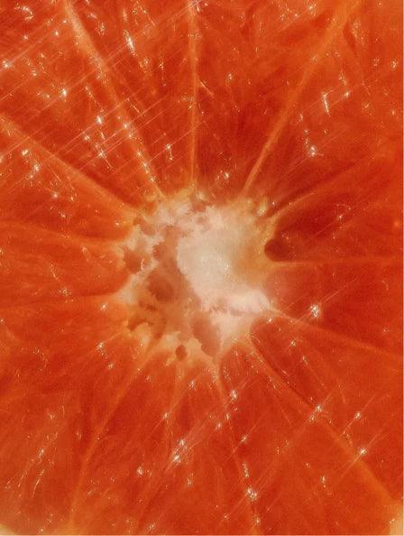 A close-up of a fresh grapefruit, highlighting its vibrant color and citrusy texture, representing the zesty fragrance of the Peachy Grapefruit Zest shampoo.